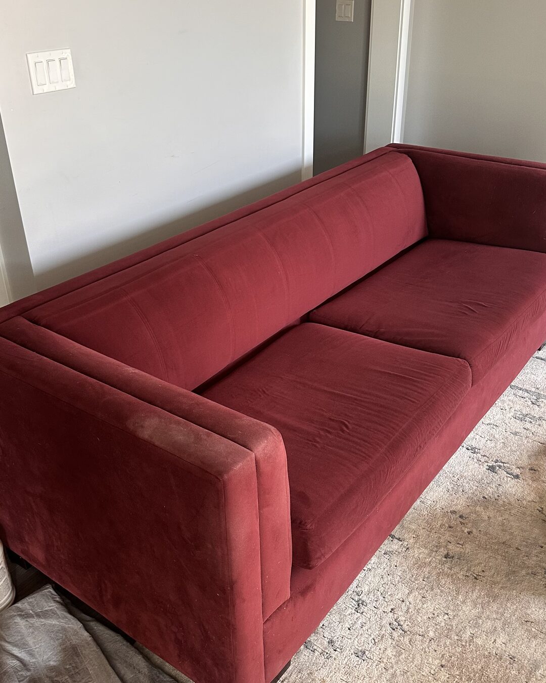 Red velvet sofa before cleaning, colour dulled by dust